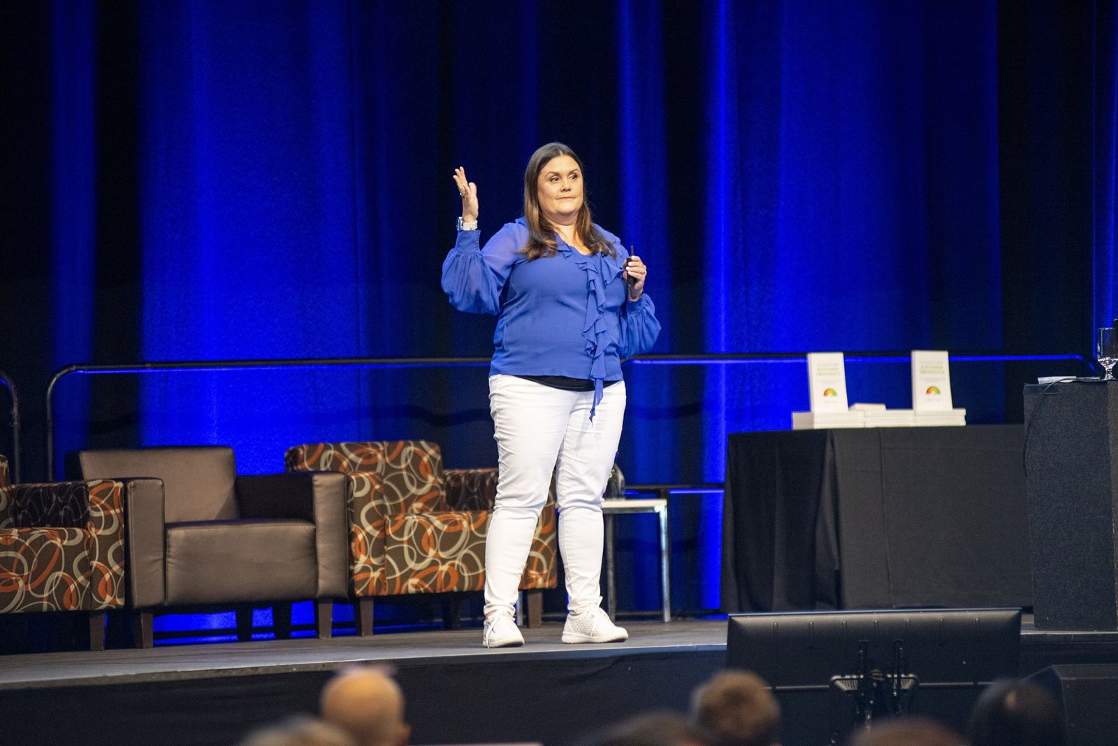 Isabella Villani speaking on stage in front of blue curtains